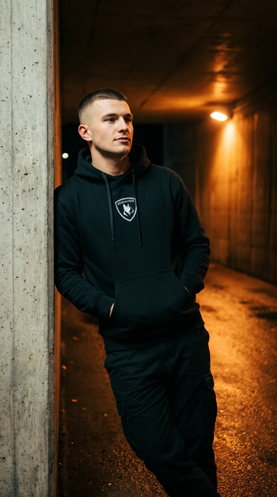 Mann im schwarzen Benhauser Classic Hoodie in einer Unterführung bei Nacht