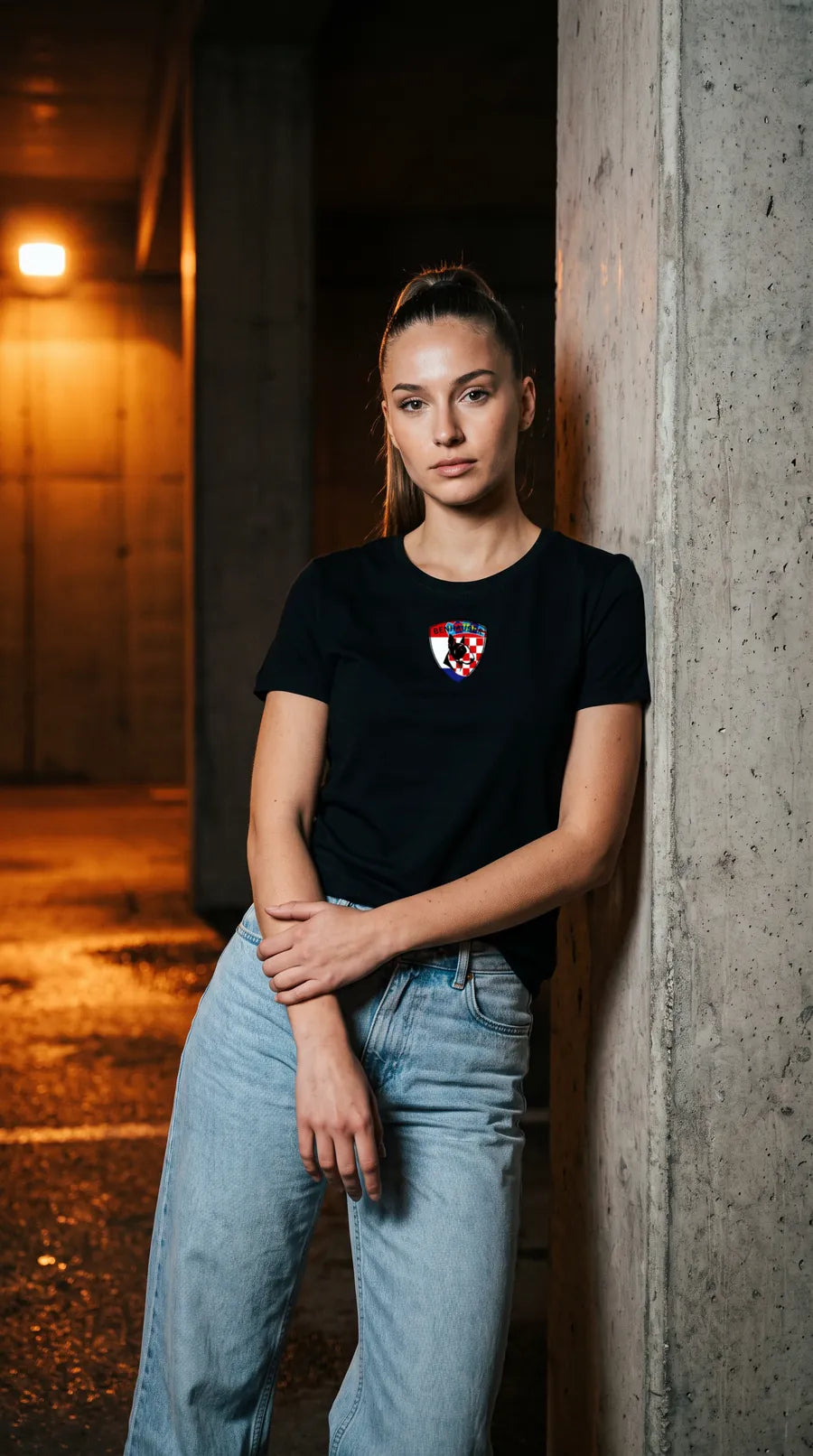 Frau im schwarzen Kroatien T-Shirt lehnt nachts an einer Betonsäule