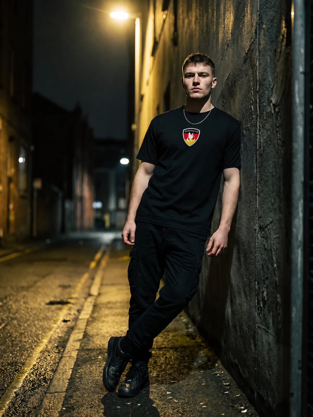 Mann im Benhauser Deutschland Shirt lehnt nachts an einer Hauswand