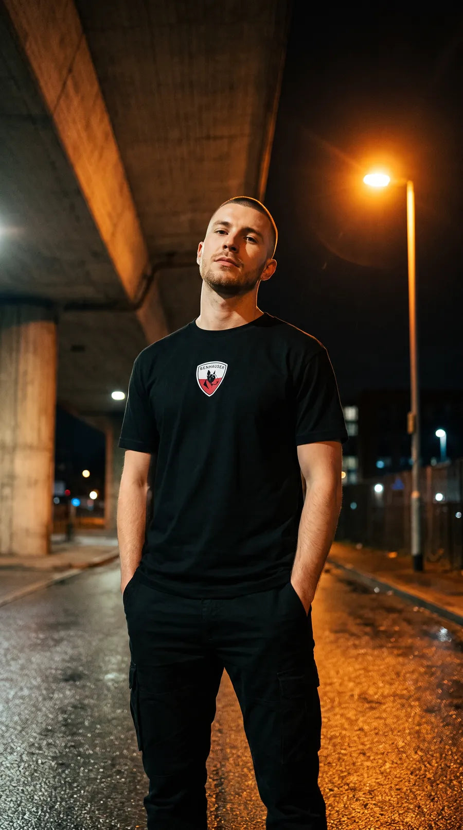 Mann im schwarzen Polen T-Shirt unter einer Überführung bei Nacht