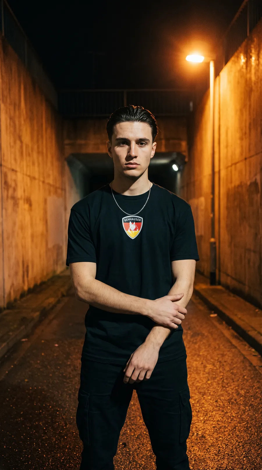 Mann im schwarzen Deutschland T-Shirt mit Benhauser Wappen unter einer Straßenlaterne